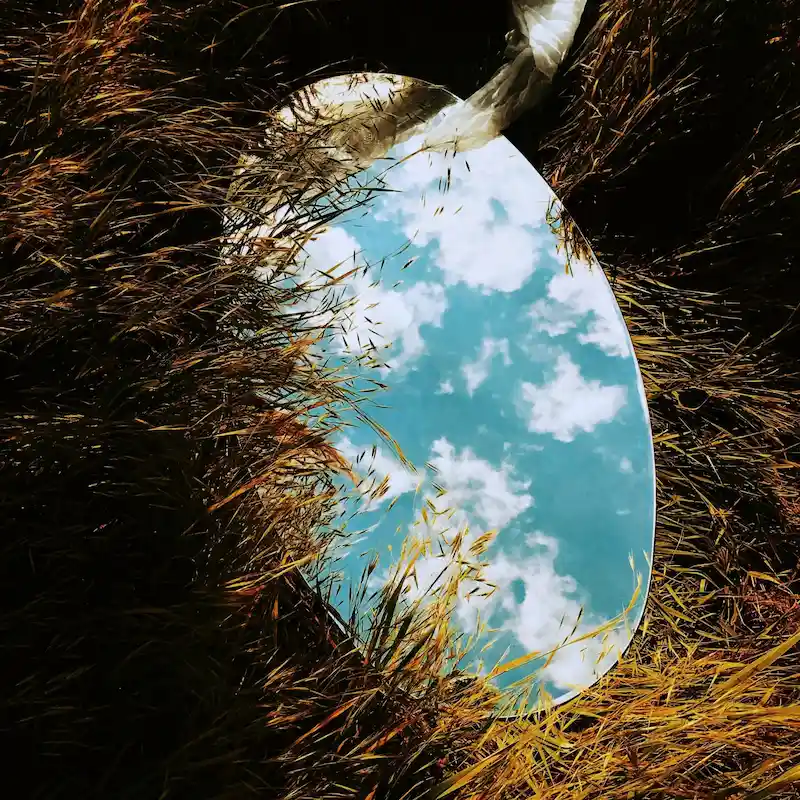 mirroir couché dans l'herbe reflétant le ciel